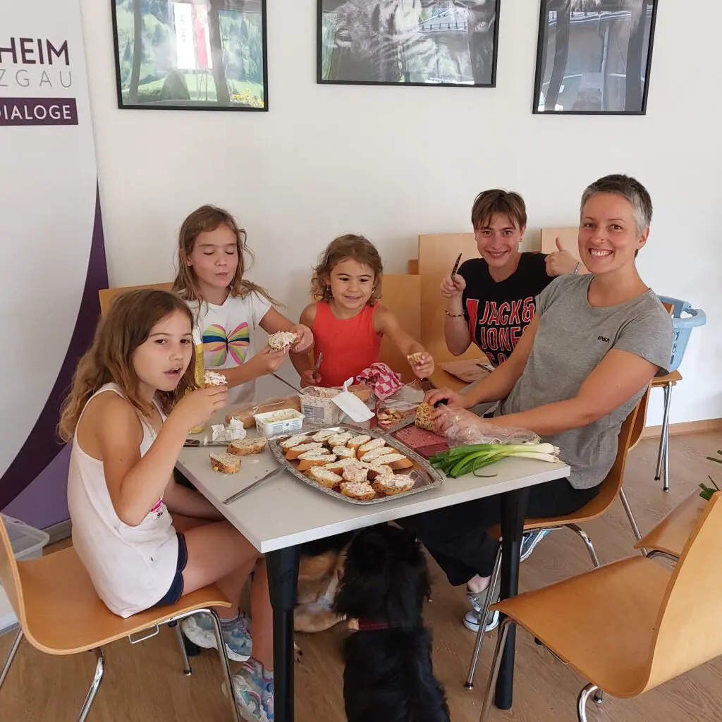 Kinder und ehrenamtliche Helfer genießen Snacks im Tierheim Pinzgau. Gemütliche Atmosphäre.